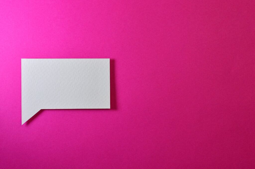 A minimalistic white paper speech bubble on a vibrant pink background, perfect for design projects.